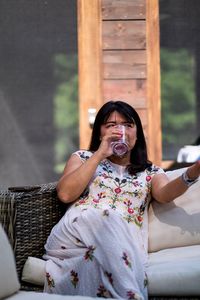 Woman drinking water while sitting on sofa