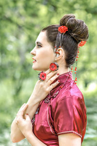 Portrait of smiling young woman looking away while standing outdoors