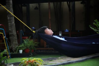 Rear view of boy sleeping on plant