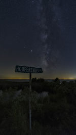 Information sign on field against sky at night