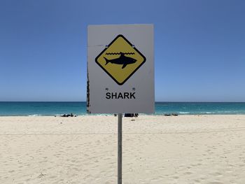 Information sign on beach against clear sky