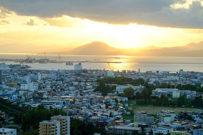 High angle view of city by sea against sky during sunset