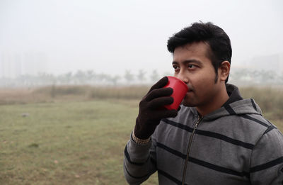 Portrait of young man holding ice cream on field