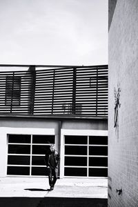 Man walking on building against sky in city