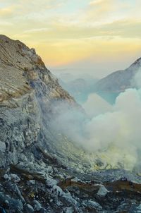 Scenic view of volcanic mountain against sky during sunset