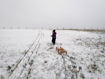 Rear view of man walking on snow covered landscape