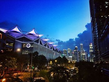 Illuminated buildings against blue sky at night