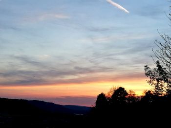 Silhouette trees on landscape against sky at sunset