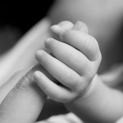 Close-up of father holding baby hand