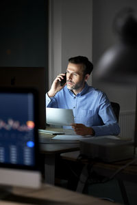 Businessman talking on phone while working late in office