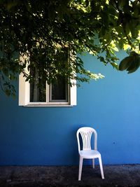 Empty chairs and tree against building