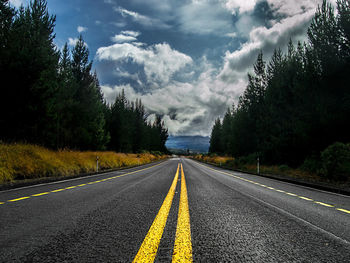 Road by trees against sky