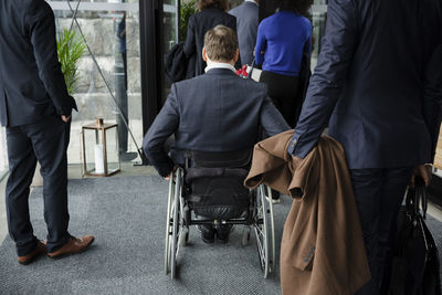 Rear view of disabled businessman with delegates entering conference center