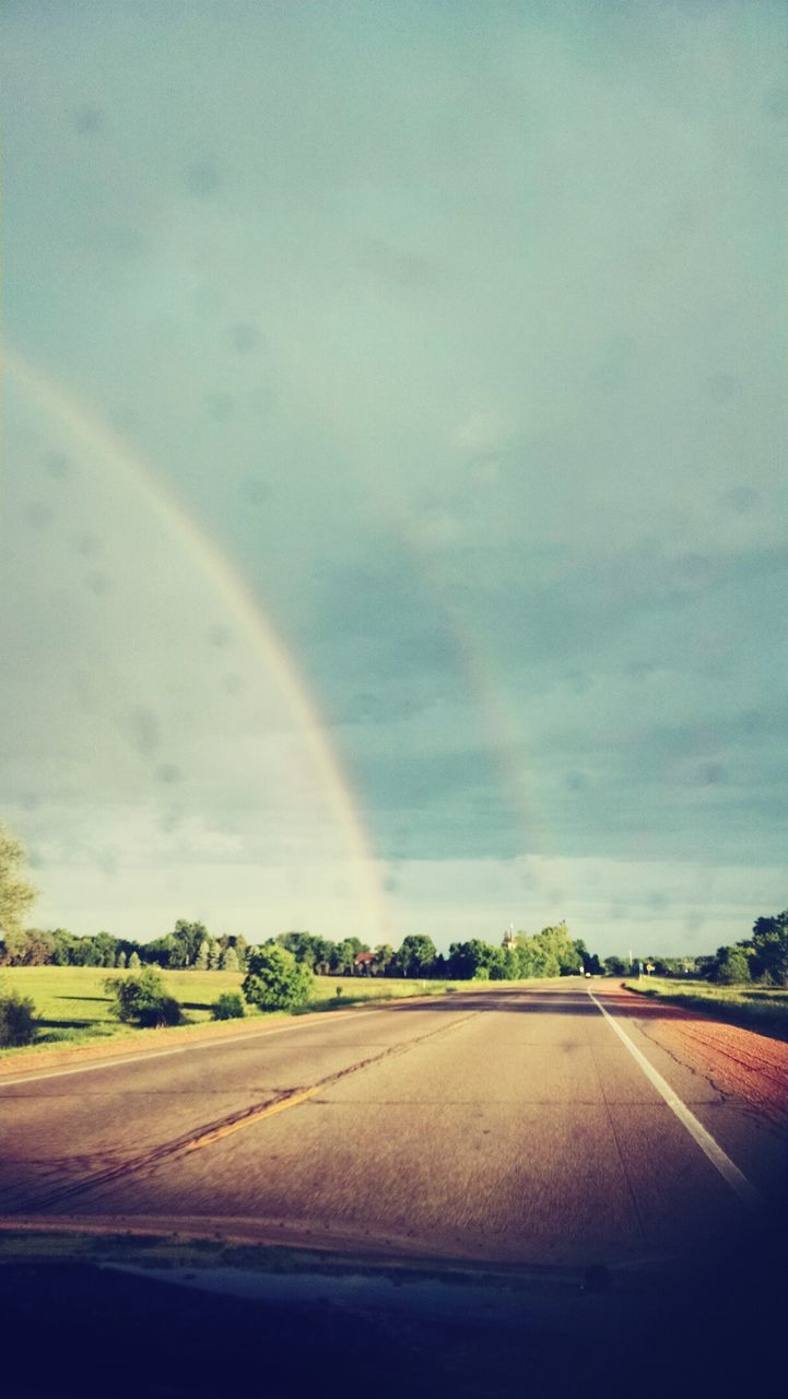 road, sky, transportation, landscape, the way forward, cloud - sky, rainbow, country road, tranquil scene, scenics, tranquility, nature, road marking, tree, beauty in nature, diminishing perspective, cloud, street, cloudy, field