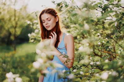 Portrait of young woman standing against plants