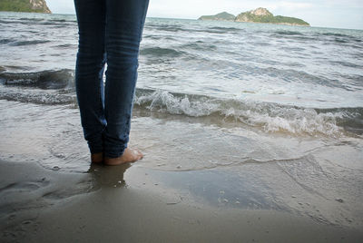 Low section of man standing on beach