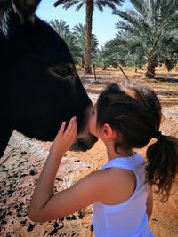 Young woman with horse on sand against sky