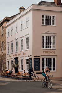 People riding bicycle on street against buildings in city