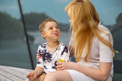 Happy blond woman and little boy sitting on terrace and eating sweets. mother and son 