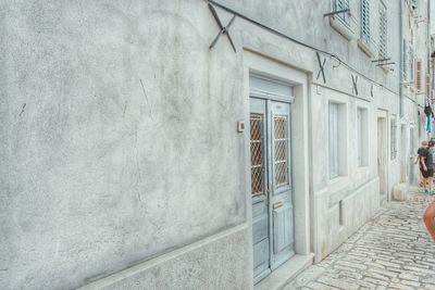 Man walking on footpath by wall of building