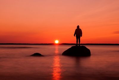 Silhouette man standing on beach against sky during sunset