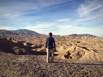 Rear view of man looking at dramatic landscape against sky