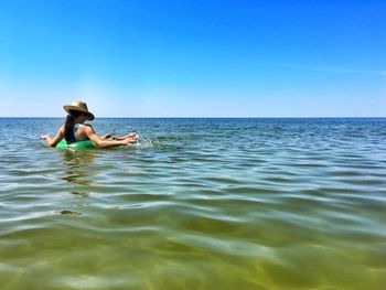 Woman relaxing in inflatable ring on sea against sky