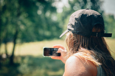 Rear view of man clicking selfie outdoors