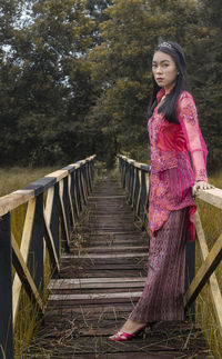Portrait of woman standing on footbridge
