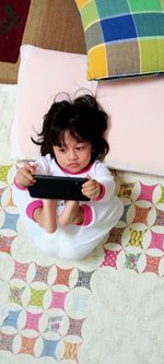 High angle view of baby girl lying on bed