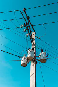 Low angle view of electricity pylon against blue sky