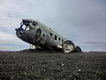 Abandoned airplane on field against sky