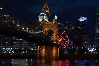 Illuminated bridge over river in city at night