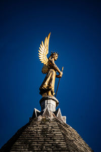 Low angle view of angel statue against blue sky