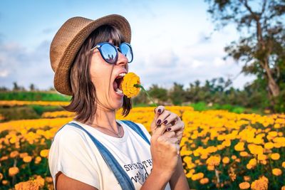 Woman eating flower with plants in background