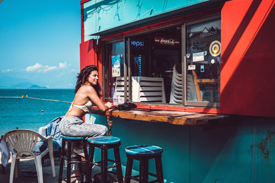 Woman sitting on table by water