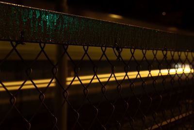 Close-up of chainlink fence against sky during sunset