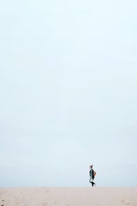 Woman walking at beach against sky