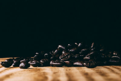 Close-up of coffee beans on table against black background