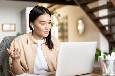 Portrait of young woman using laptop at home