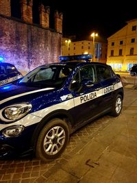 Car on street by illuminated buildings in city at night