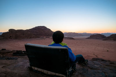 Rear view of man sitting on land