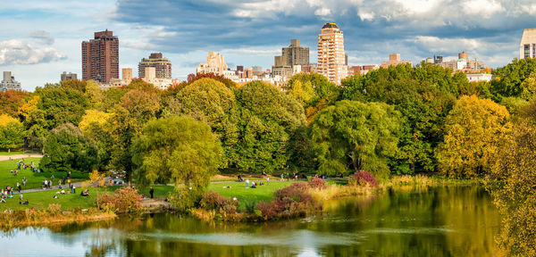 Scenic view of lake by trees in park against sky