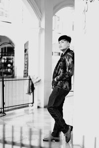 Side view of young woman standing against building