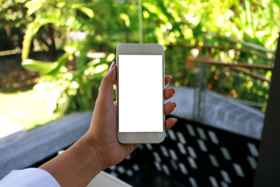 Cropped image of woman holding mobile phone outdoors