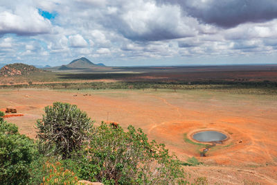 A watering hole in savannah grassland landscapes against mountains at tsavo east national