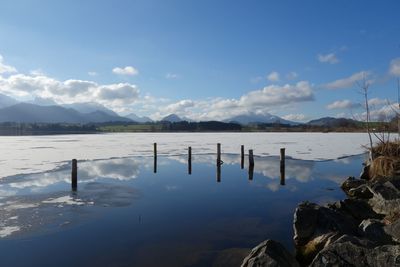 Wooden posts in lake against sky