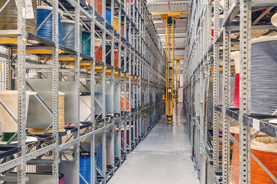 Interior of modern storage warehouse with coils of colored cable on metal shelves. forklift 