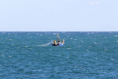 Boat sailing in sea against clear sky