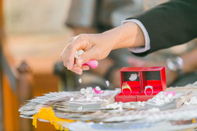 Cropped hands of man decorating wedding rings with flower petals